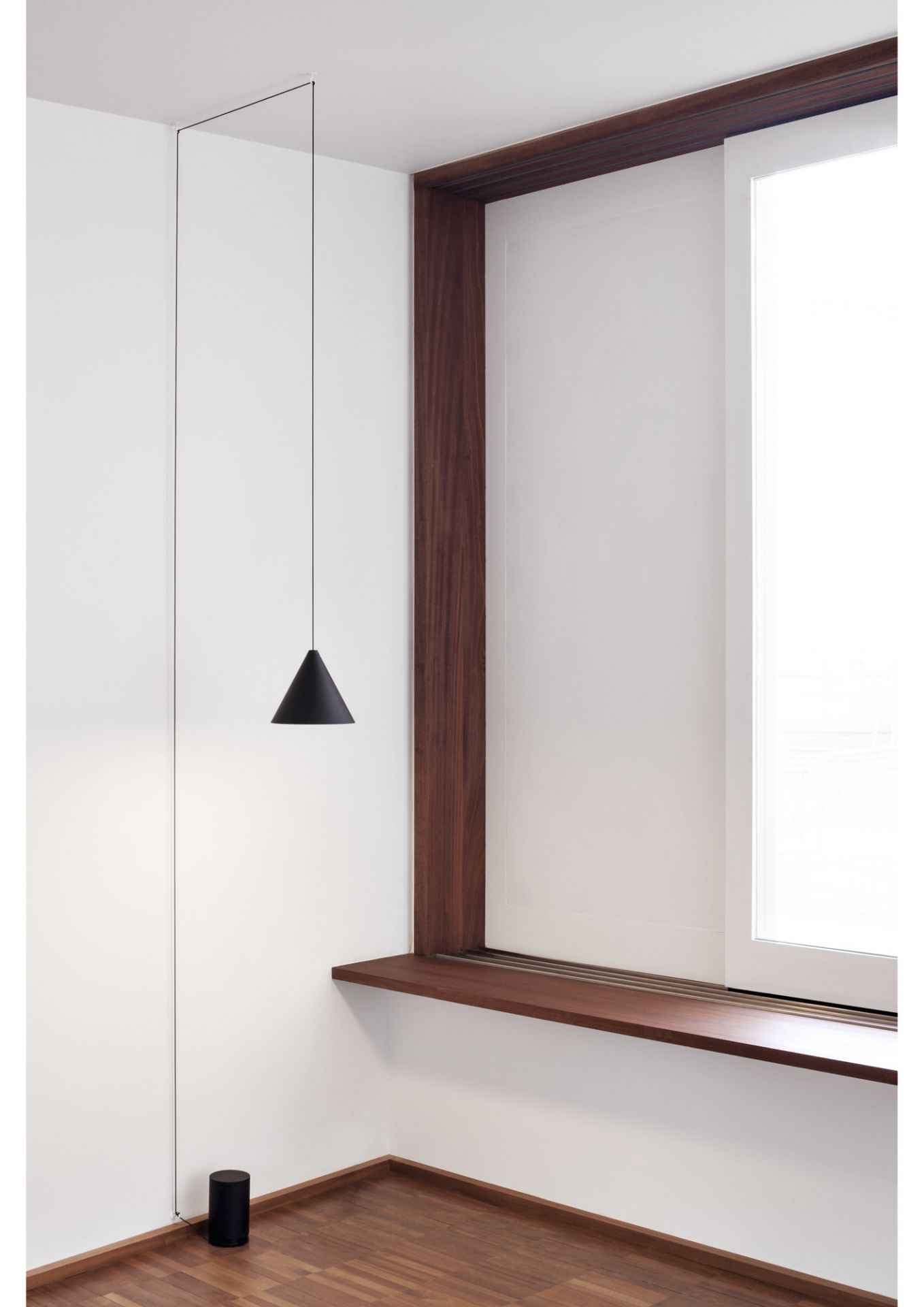 Schwarze Flos Pendelleuchte mit String Light und Bodenschalter in minimalistischem Raum.